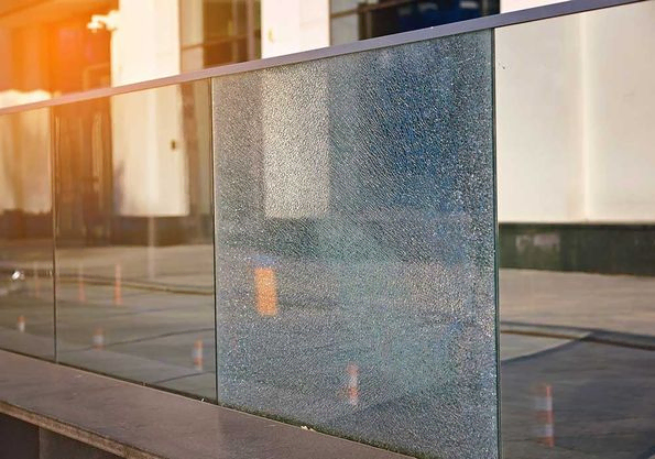 Beschädigter Zaun aus gehärtetem Glas. Zerbrochener Glaszaun mit Geländer. Defektes Geländer auf der Büroterrasse.
